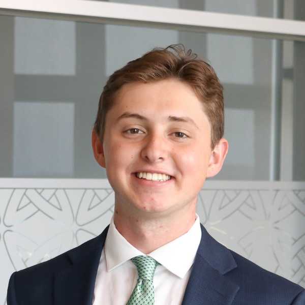 Professional headshot of Andrew Rocks, wearing navy suit and green tie